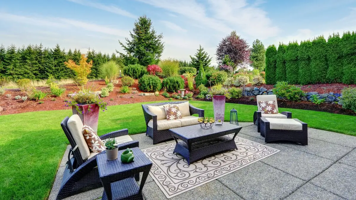A beautifully landscaped yard featuring a stylish patio with outdoor furniture, lush greenery, and vibrant flower beds — Beyond Lawn Care.